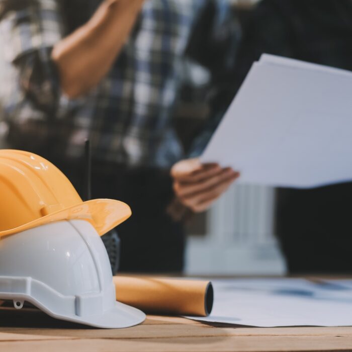 Asian young female architect discussing with japanese male building manager contractor for quality control site inspection and at house construction site in room under renovation project.